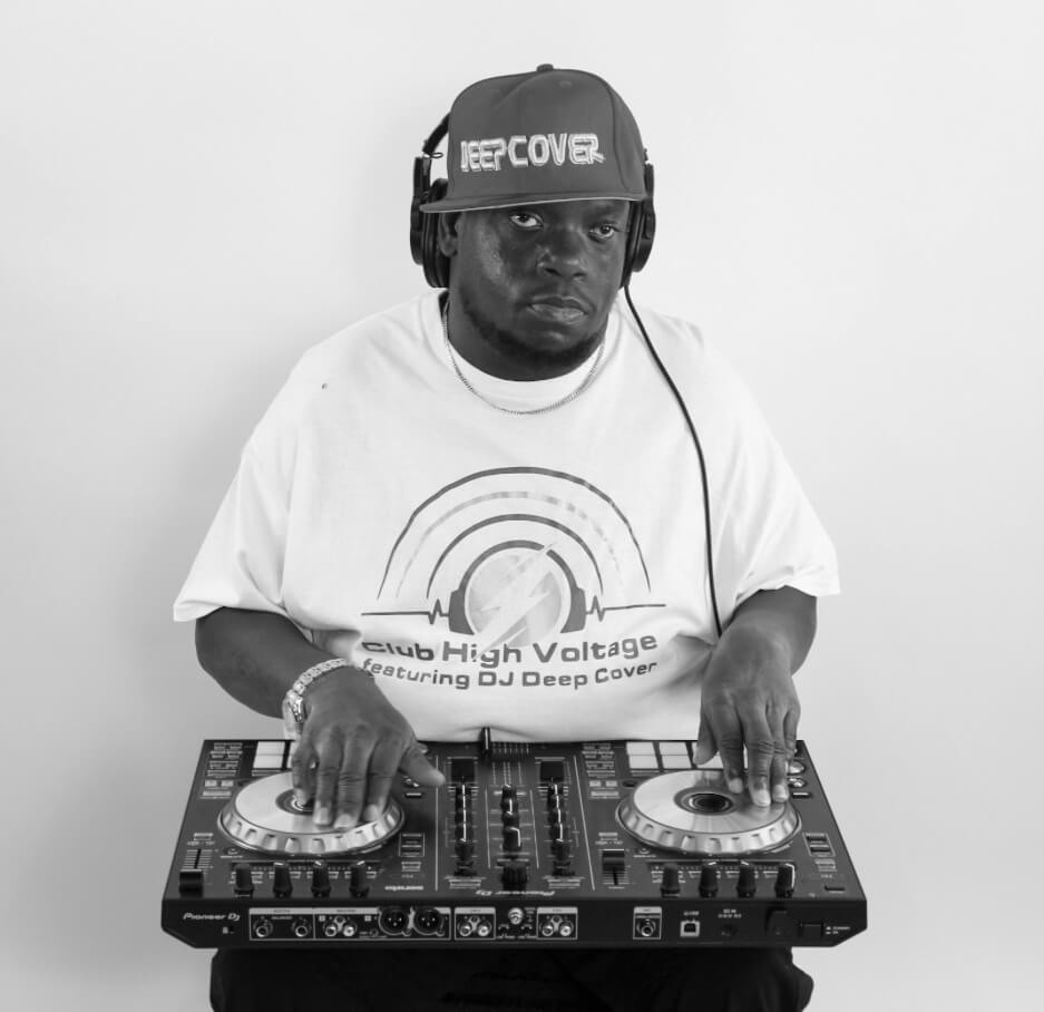 DJ Deep Cover mixing on a Pioneer controller in a Club High Voltage shirt